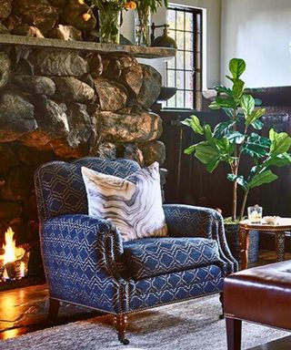 blue patterned upholstered armchair with cushion by lit fire