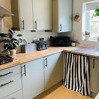 Green kitchen with black and white striped curtain