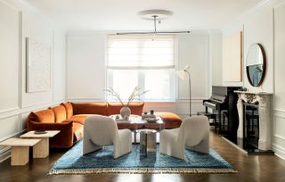 white living room with blue rug and orange chairs