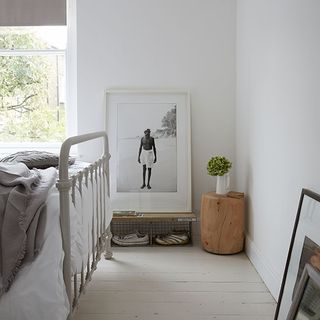 bedroom with white wall wooden block at corner framed photo and wooden flooring
