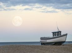 The moon rises during the daytime at Dungeness, Kent.