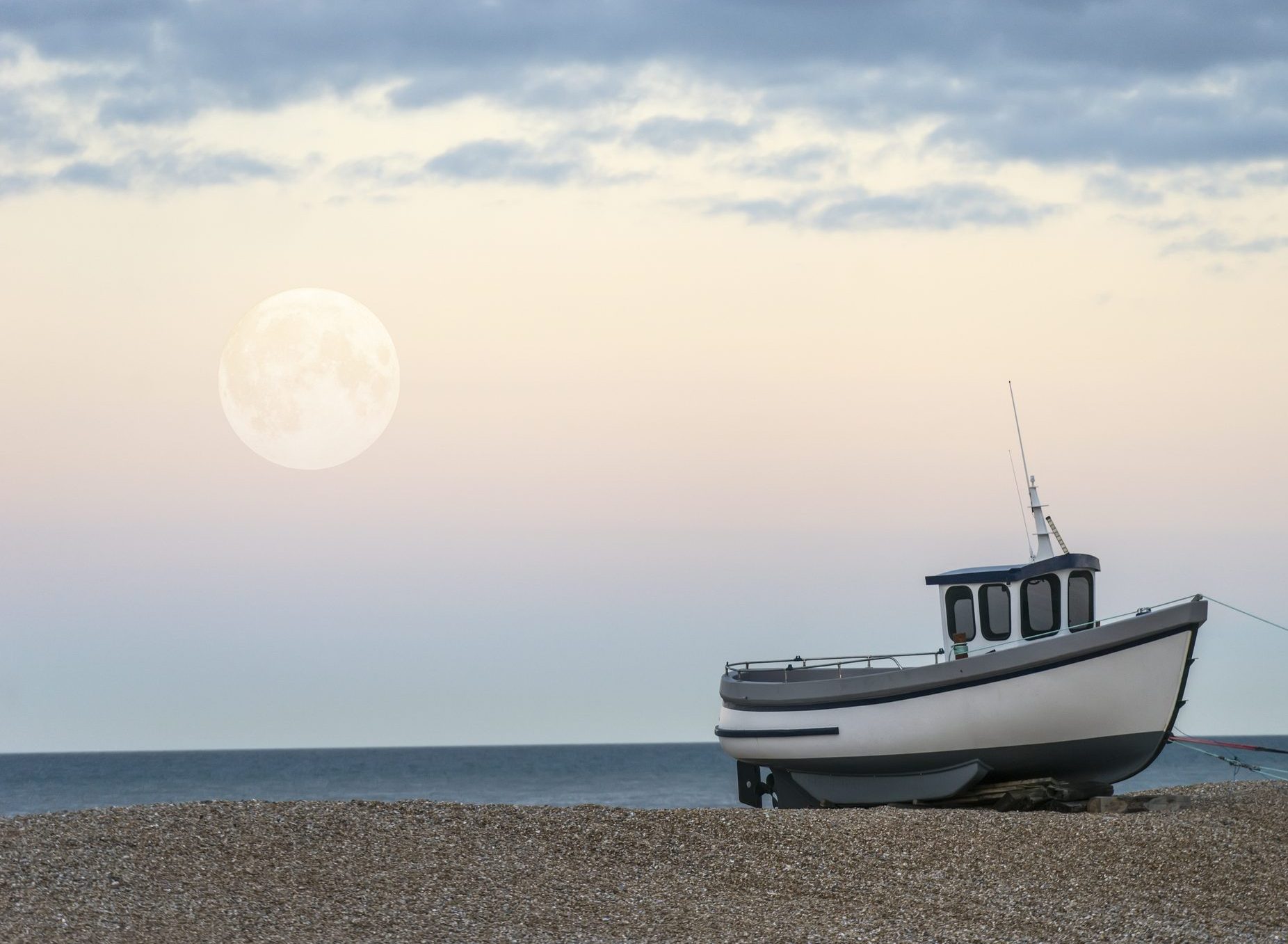 The moon rises during the daytime at Dungeness, Kent.