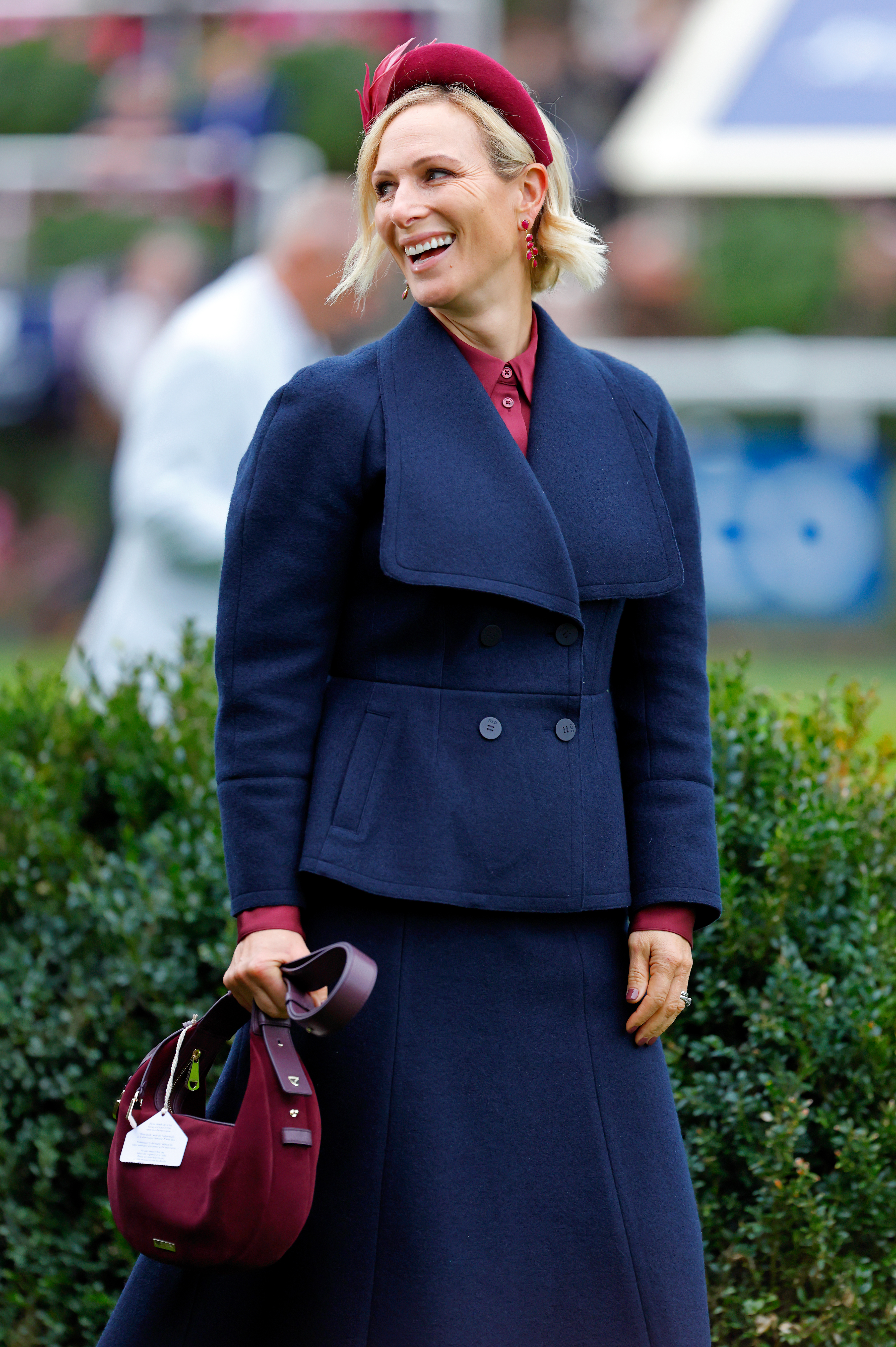 Zara Tindall wearing a navy coat and burgundy bag
