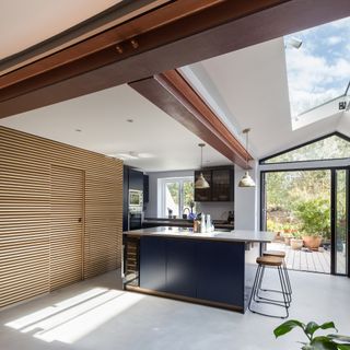 a kitchen with a long rooflight, sliding patio doors, navy blue kitchen cabinetry. plenty of storage and a kitchen island