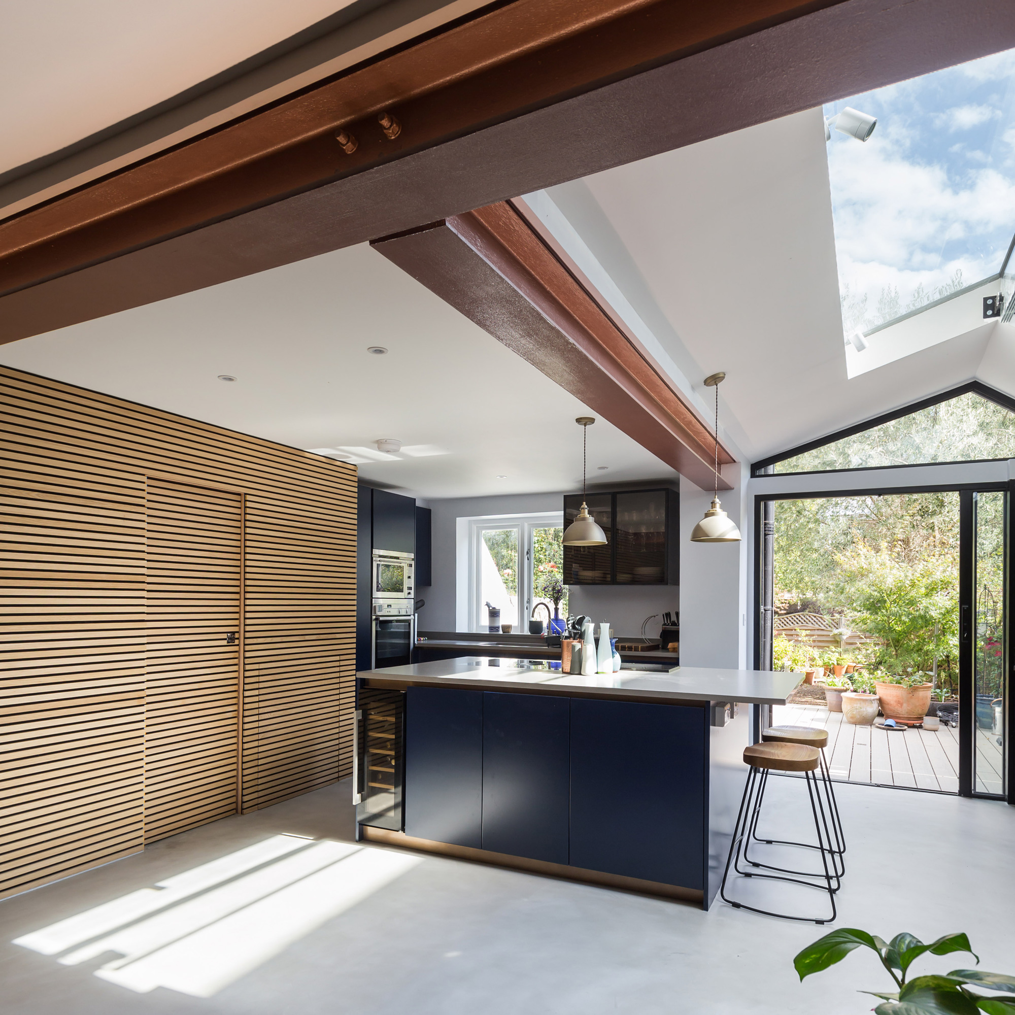 a kitchen with a long rooflight, sliding patio doors, navy blue kitchen cabinetry. plenty of storage and a kitchen island