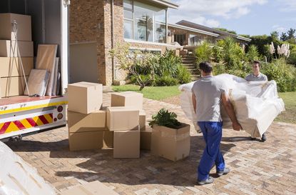 Movers carrying sofa from moving van to house