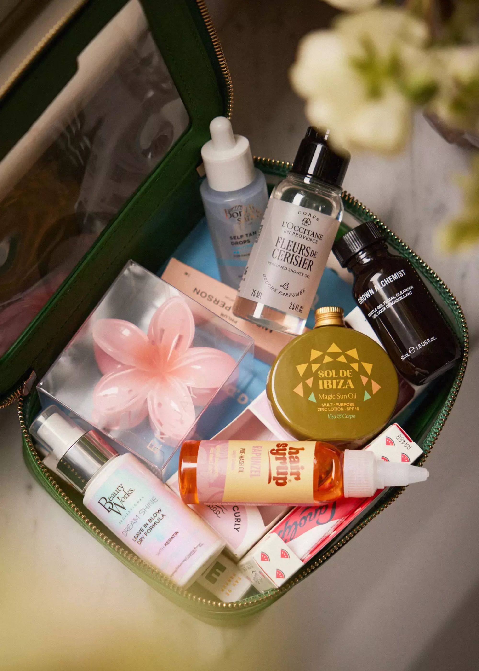 An overhead close-up of a toiletry wash bag full of skincare and accessories