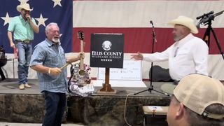 A man holds a hammer and the Taylor Swift acoustic guitar he won at auction for $4,000