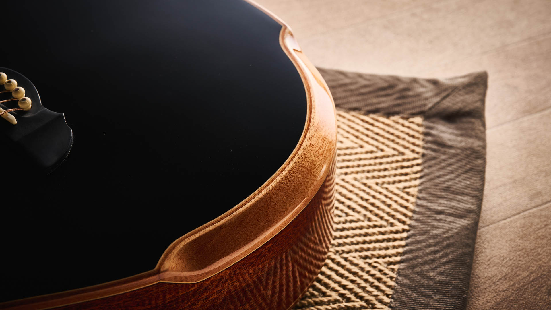 Harley Benton CLC-650SM-CE: the affordable cutaway electro-acoustic has a black top, natural back and sides, with an attractive arm-rest and tortoiseshell pickguard, and is here photographed against a wooden floor.