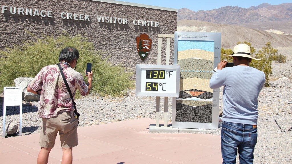 People taking pictures of an unofficial thermometer reading 130 F near the Furnace Creek visitor center in Death Valley National Park.