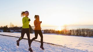 Two women running through the snowy countryside