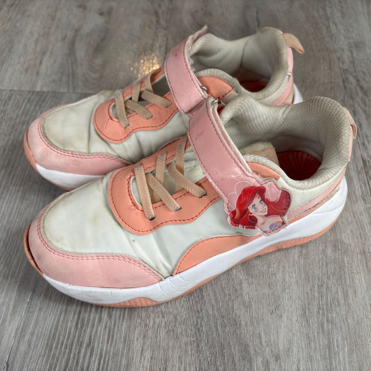 Clean pink and white trainers on grey flooring
