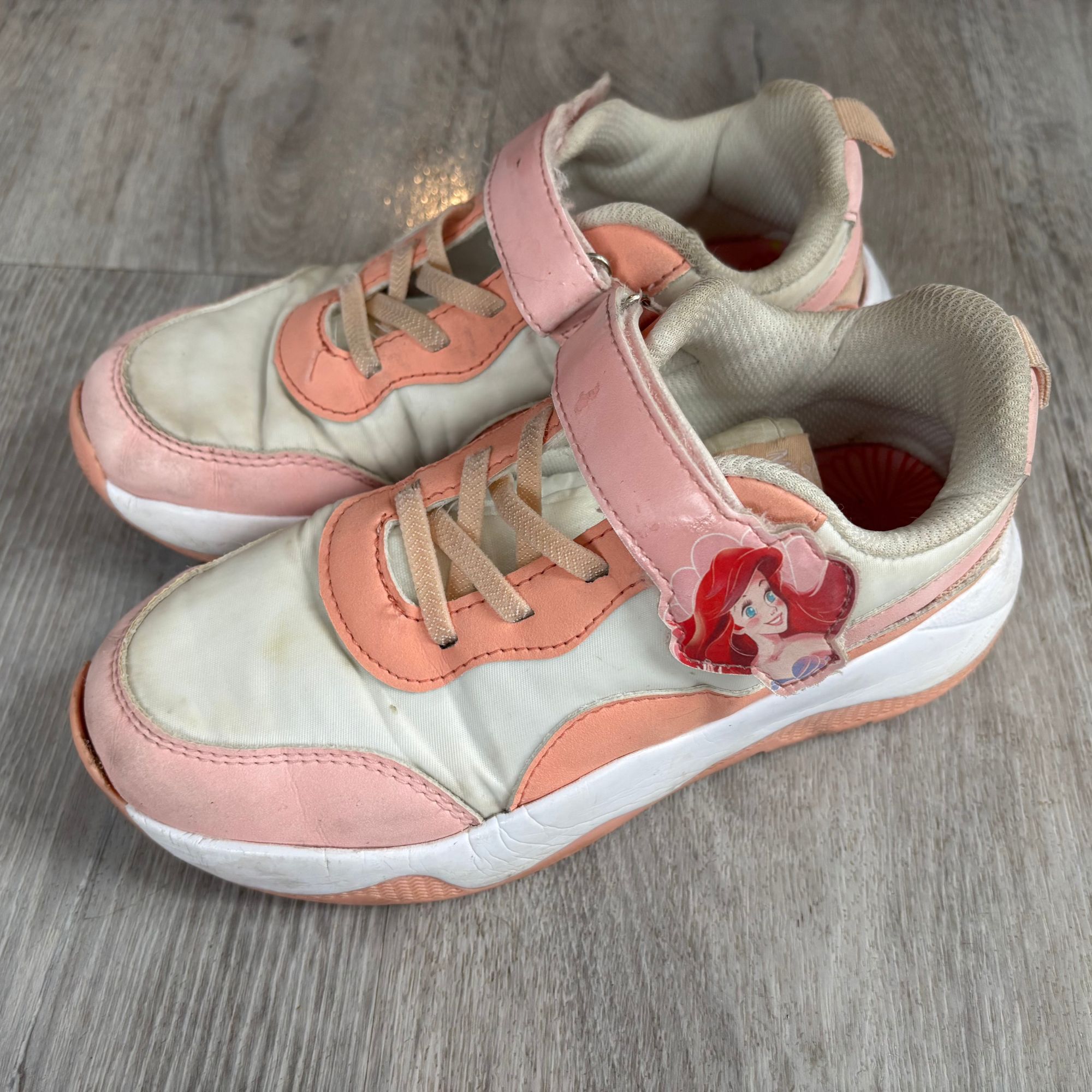 Clean pink and white trainers on grey flooring