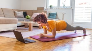 Woman holds plank exercise at home