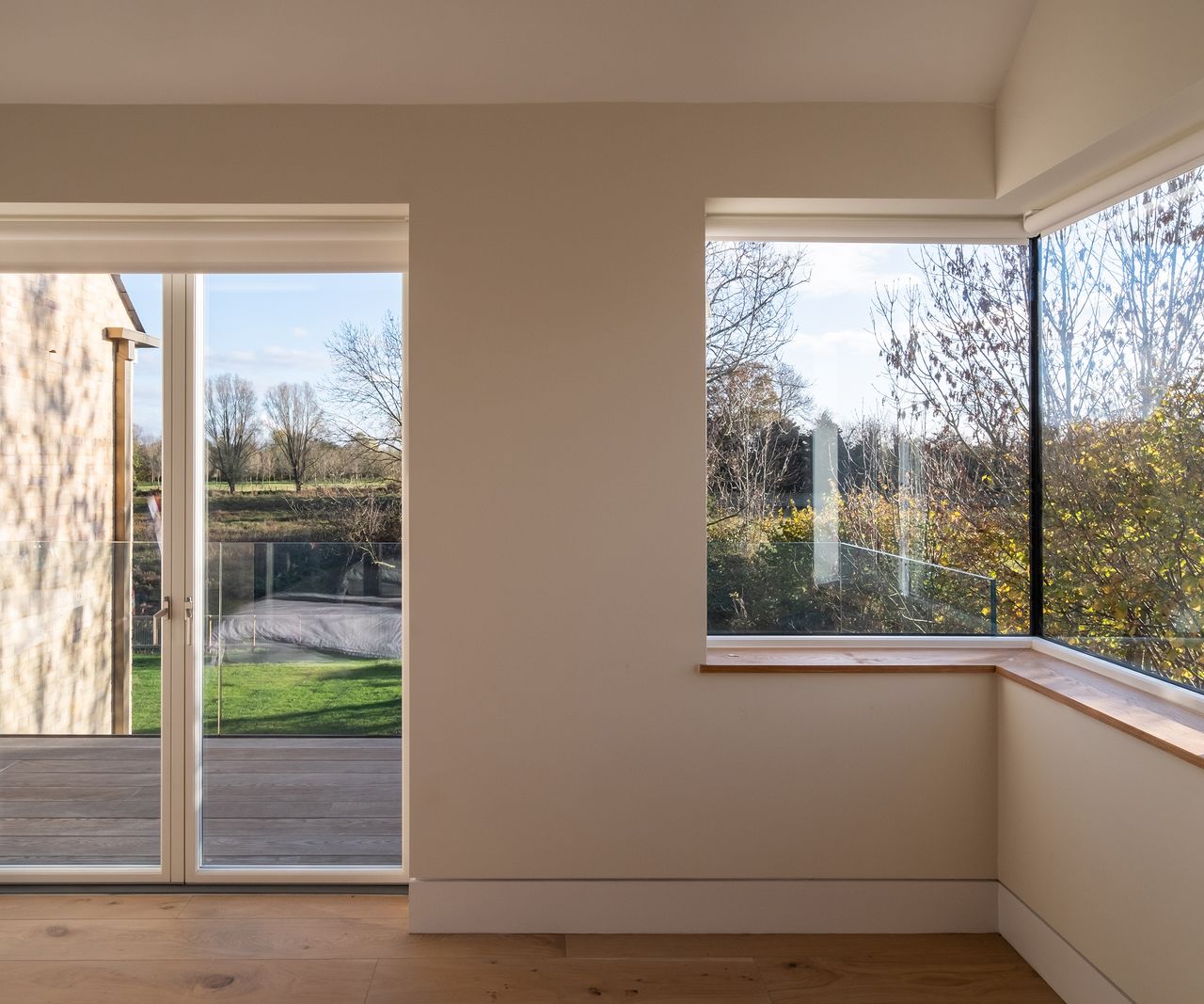 A room of a self build home filled natural light and doors opening out onto a small wooden balcony terrace with views