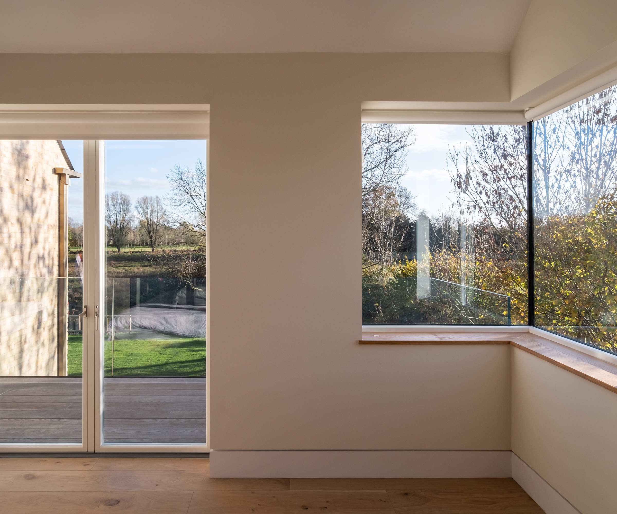 A room of a self build home filled natural light and doors opening out onto a small wooden balcony terrace with views