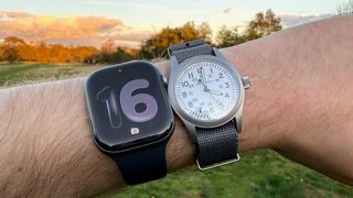 An image of the Apple Watch Series 11 on a wrist alongside a mechanical watch