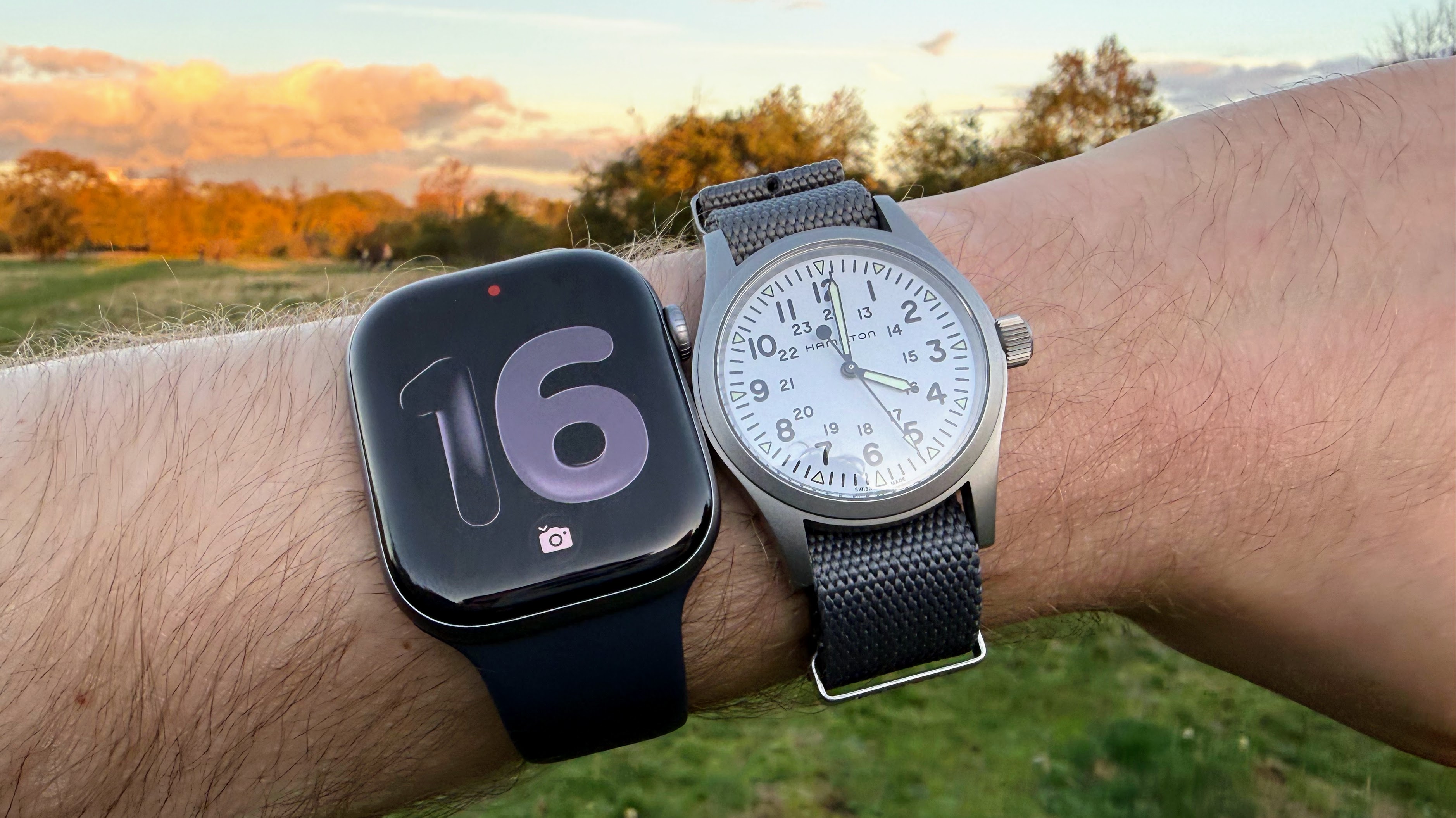 An image of the Apple Watch Series 11 on a wrist alongside a mechanical watch