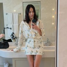 Alexa Chung wearing a Dior floral shirt and matching miniskirt in a bathroom selfie. 