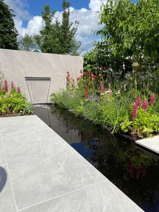 water feature and pond at The 'Lower Barn Farm: Bounce Back' garden designed by Consilium Hortus at hampton court flower show 2021