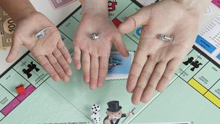 Three hands holding monopoly counters