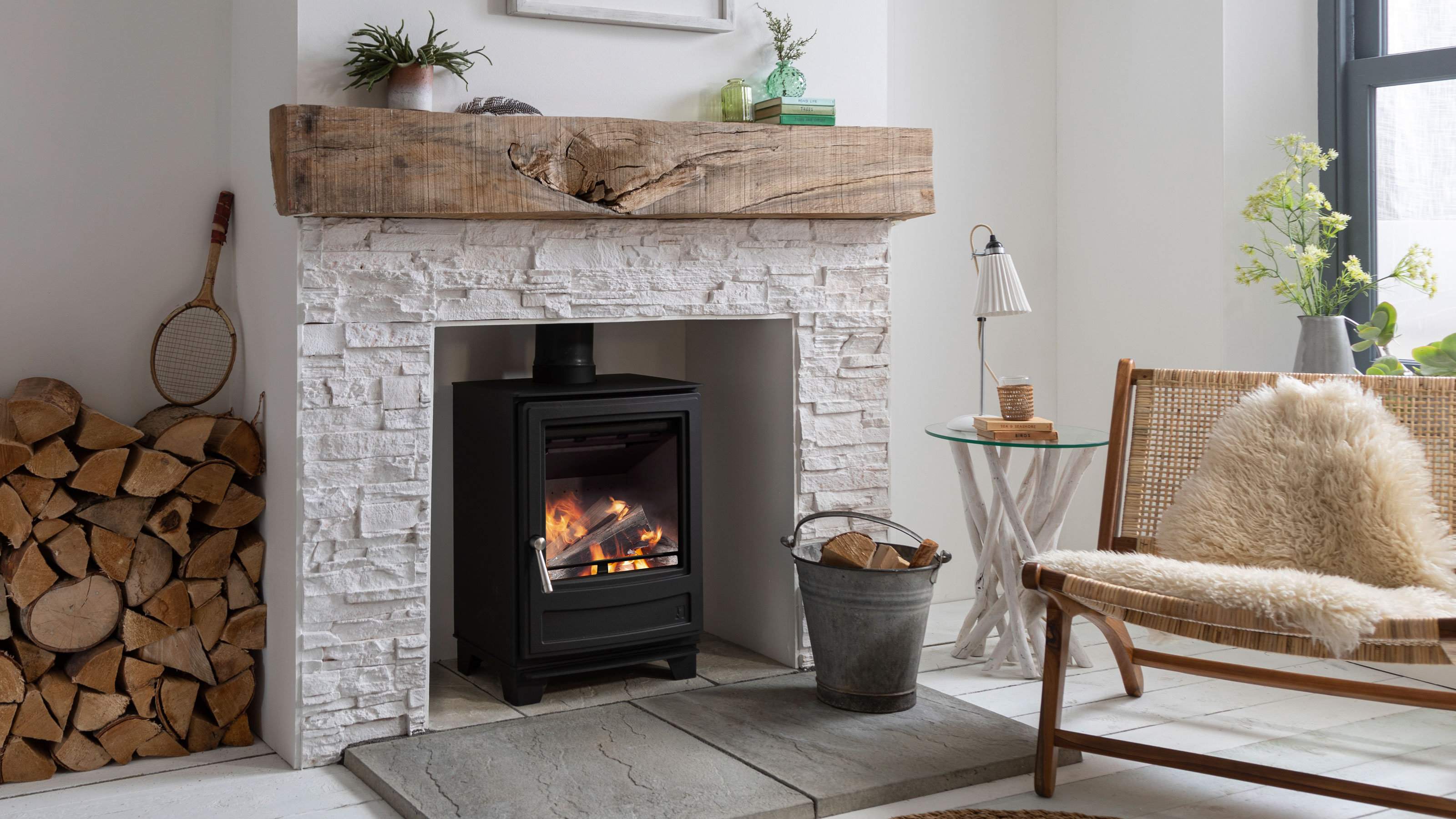 black cast iron log burning stove within white brick fireplace with chunky oak mantle