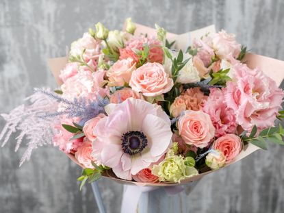 A beautiful bouquet of light pink flowers and foliage in a vase