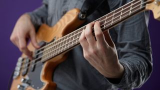 Best beginner bass guitars: Man playing bass against purple background