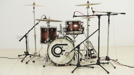 A drum kit in a studio with drum mics around it