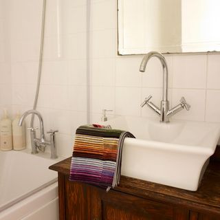 bathroom with wash basin and towel with mixer tap and white wall tiles