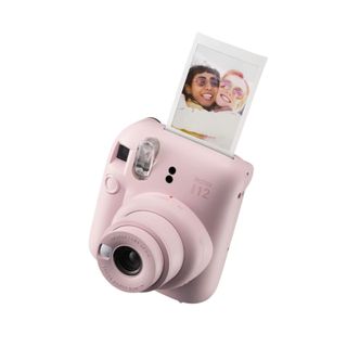 A pink polaroid camera with a picture coming out of it