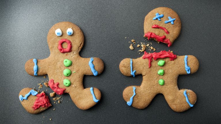 A shocked gingerbread man with broken leg next to a decapitated gingerbread man - stock photo