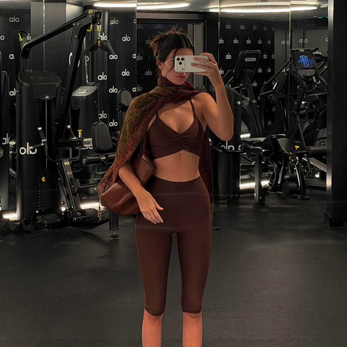 Kendall Jenner at the Alo gym wearing a brown sports bra and cropped brown leggings.