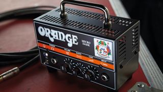 An Orange Micro Dark mini guitar amp head on top of a flight case