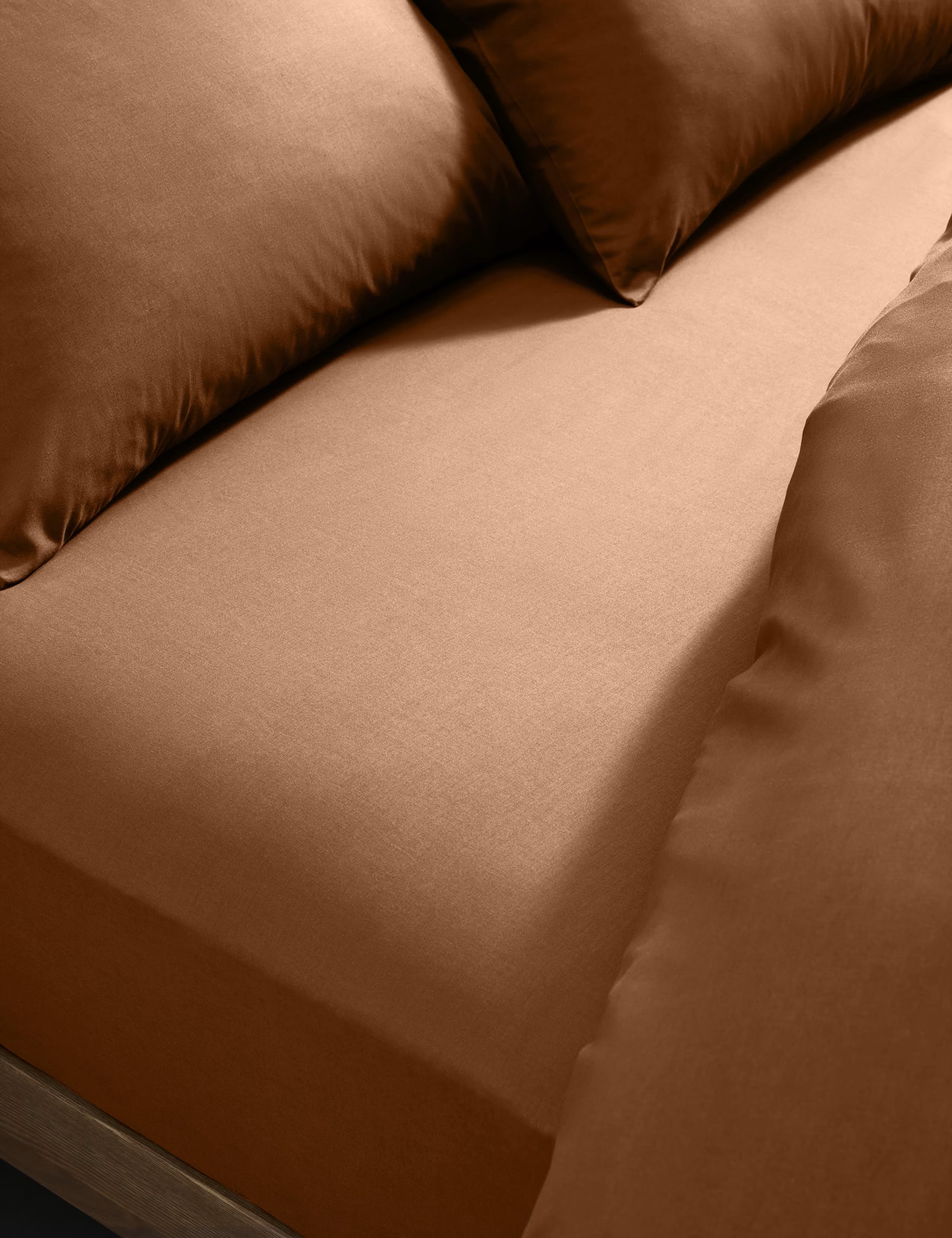 Close up image of a rust orange bedsheets on a bed