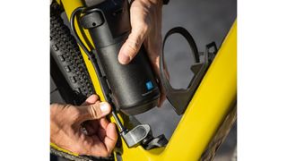 Male cyclist holding a spare battery and plugging it in to the Scott Solace eRide bike near the bottom bracket of the bike