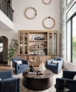Neutral living area with jean blue armchairs surrounding coffee table and drinks cabinet in the distance