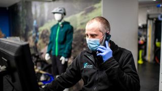 A bike shop sales assistant speaks on the phone whilst working on a computer