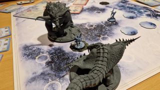 Two massive monster miniatures face off with one another on the Monster Hunter World: Iceborne board