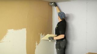 Plasterer skimming a plasterboard wall