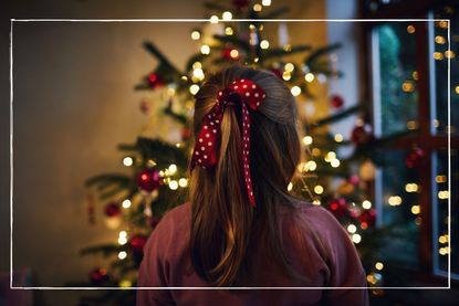 Young girl looking at Christmas tree with lights on