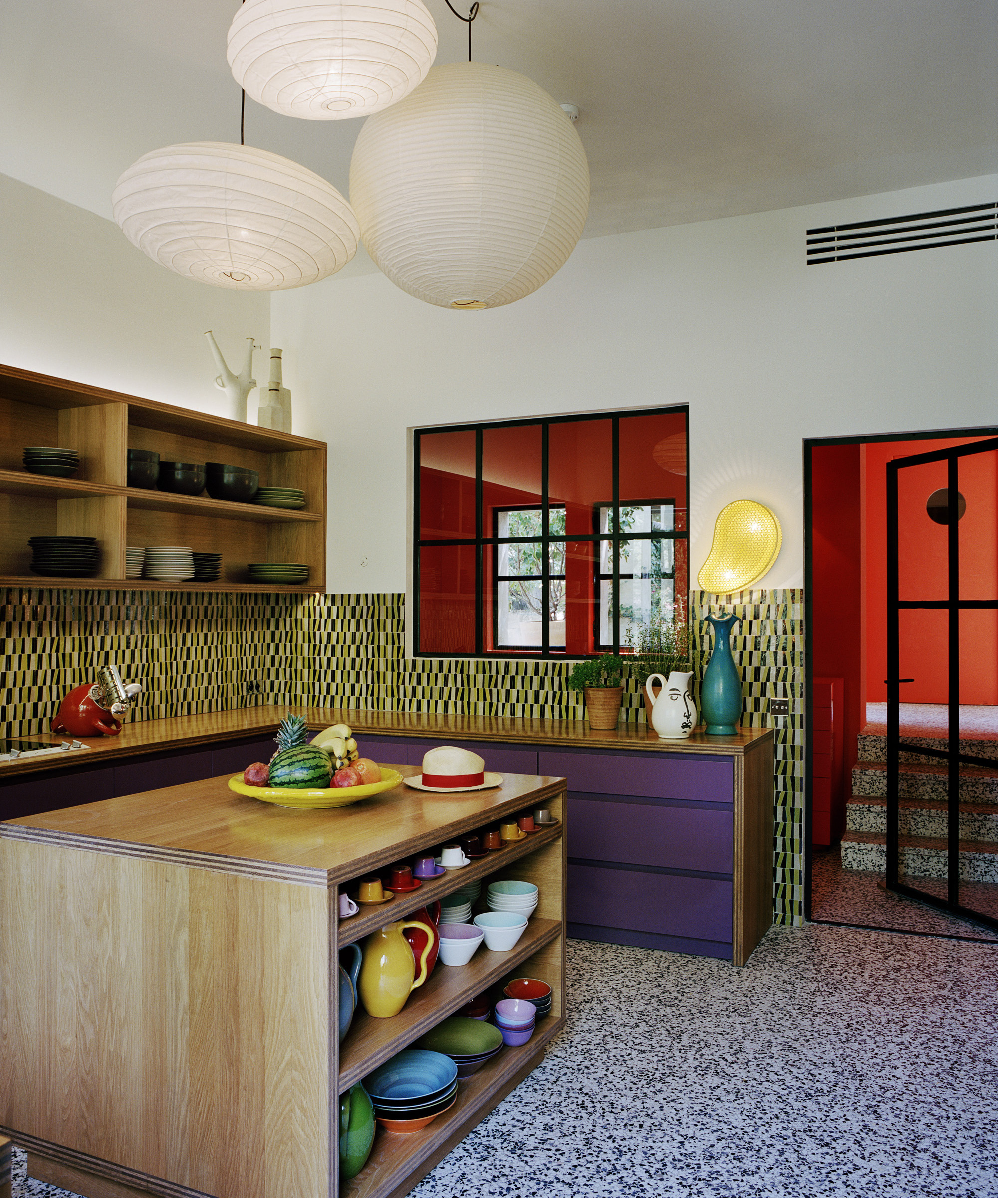 kitchen with green backsplash, wood island and red room beyond