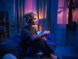 Gamer wearing the Logitech G Astro A20 X Lightspeed Wireless Gaming Headset in a living room. 