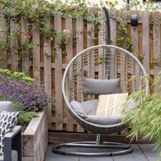Hanging egg chair in garden patio against fencing