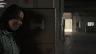 Sophie hiding behind some crates in The Couple Next Door episode 4.