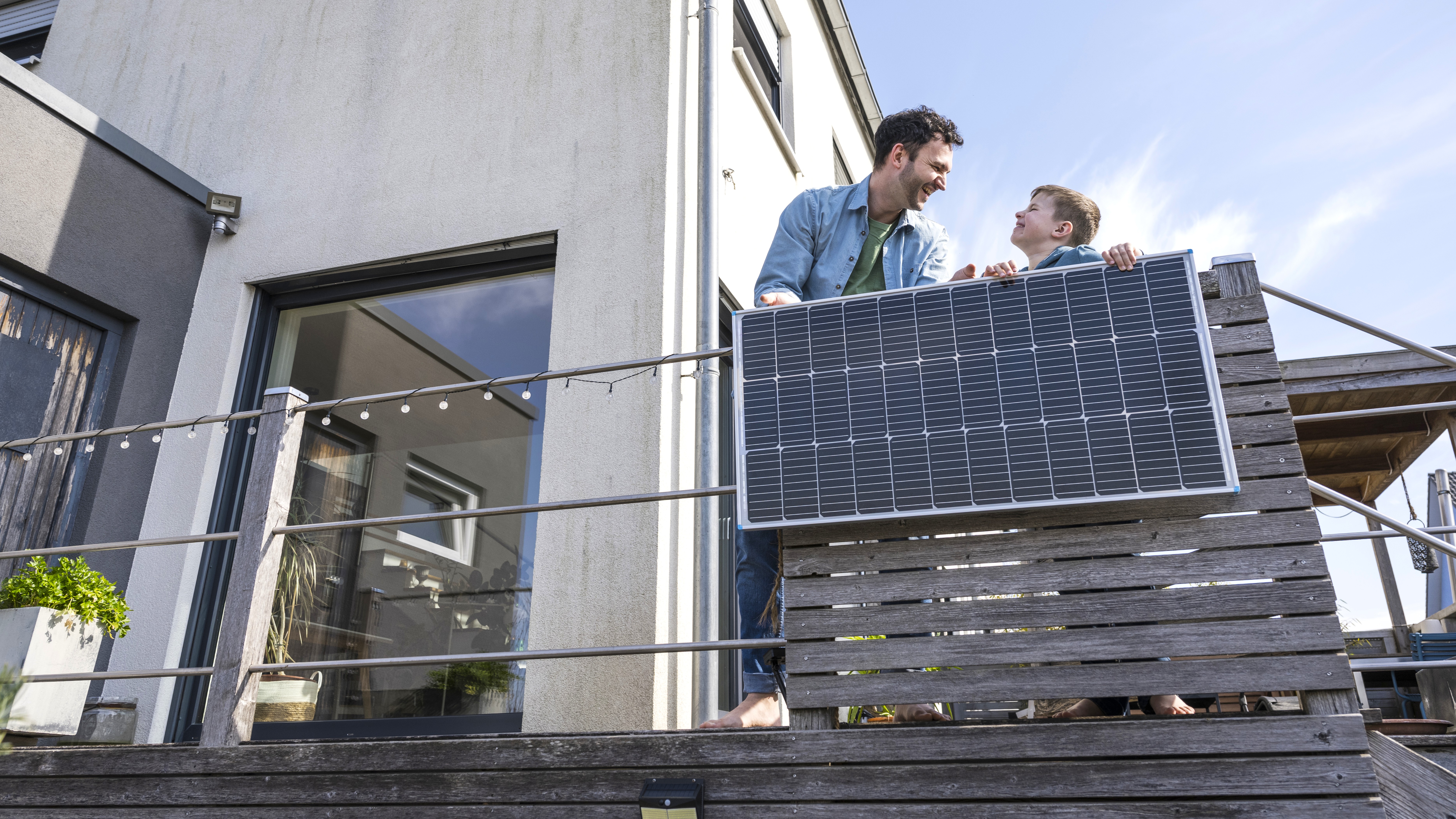 Man and boy standing on balcony with solar panel installed