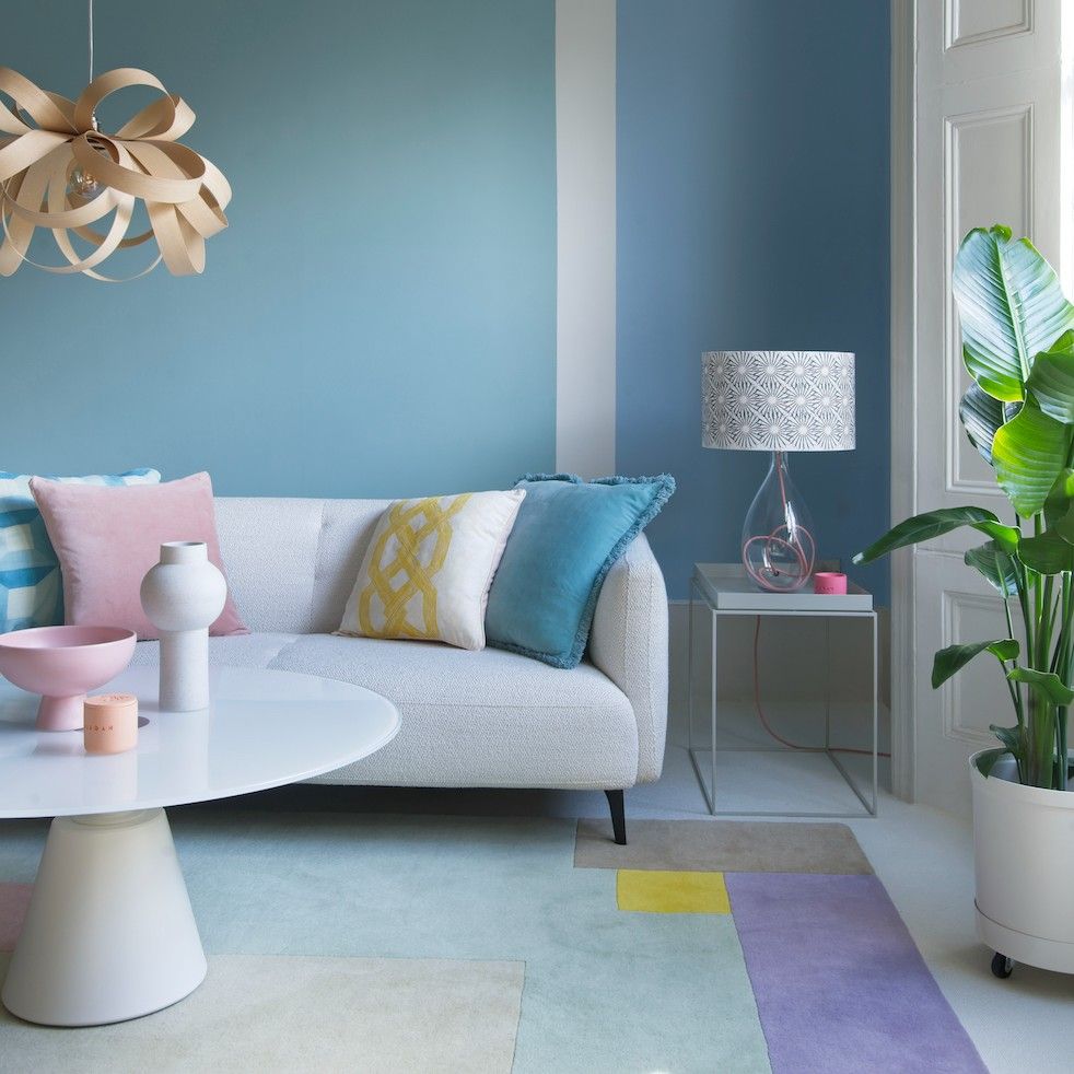 living room with blue wall and sofa with cushions and lamp on side table