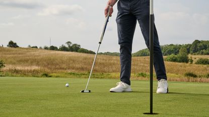 Pressing down old hole plug on the line of a putt