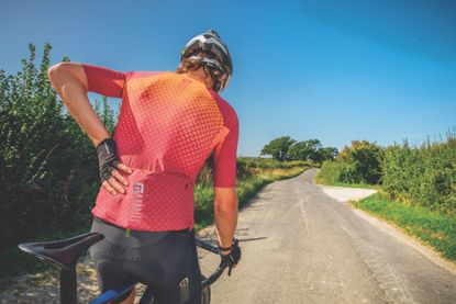 Image shows a cyclist suffering with back pain