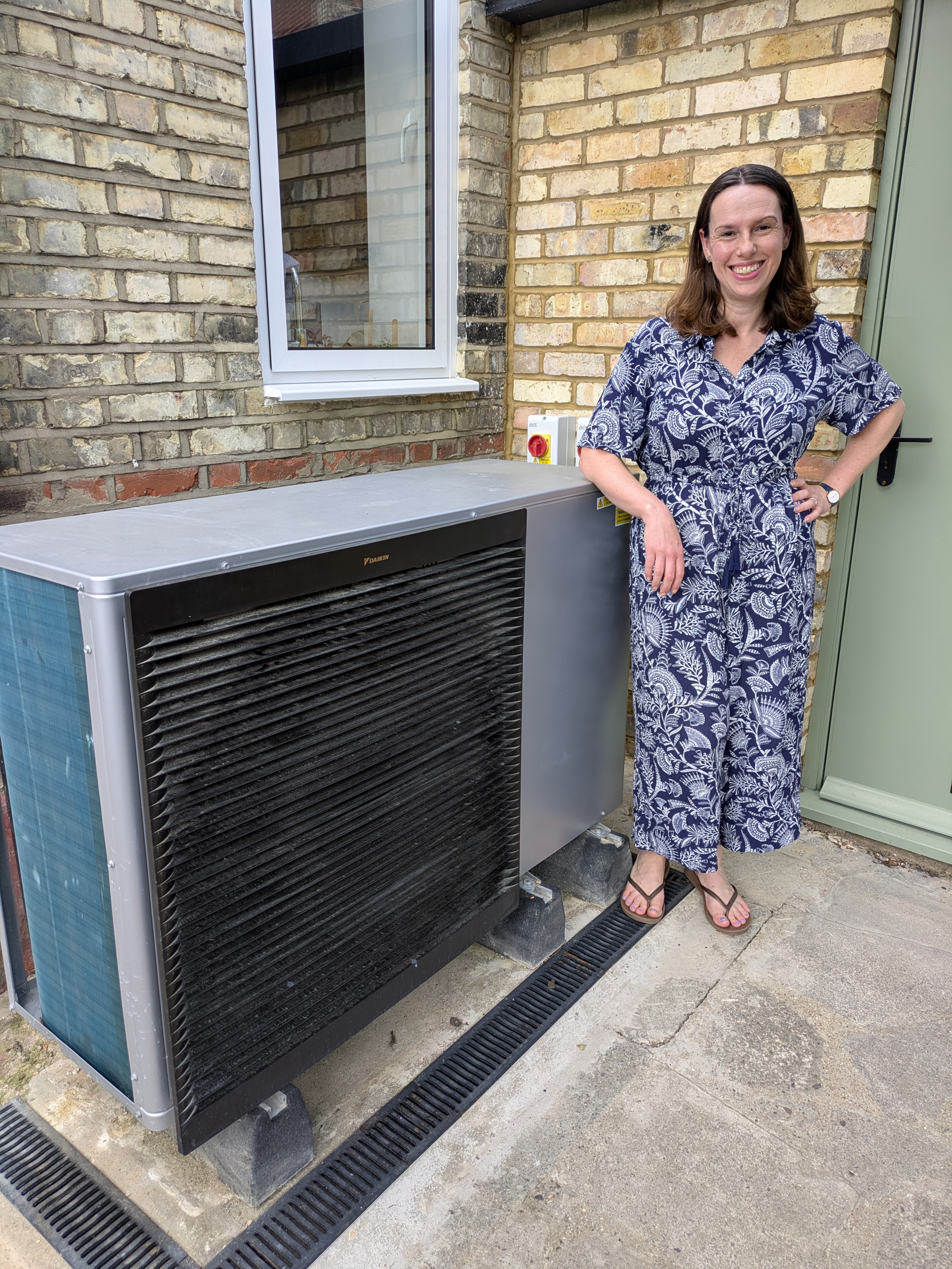 Ruth Emery stands beside heat pump in her garden